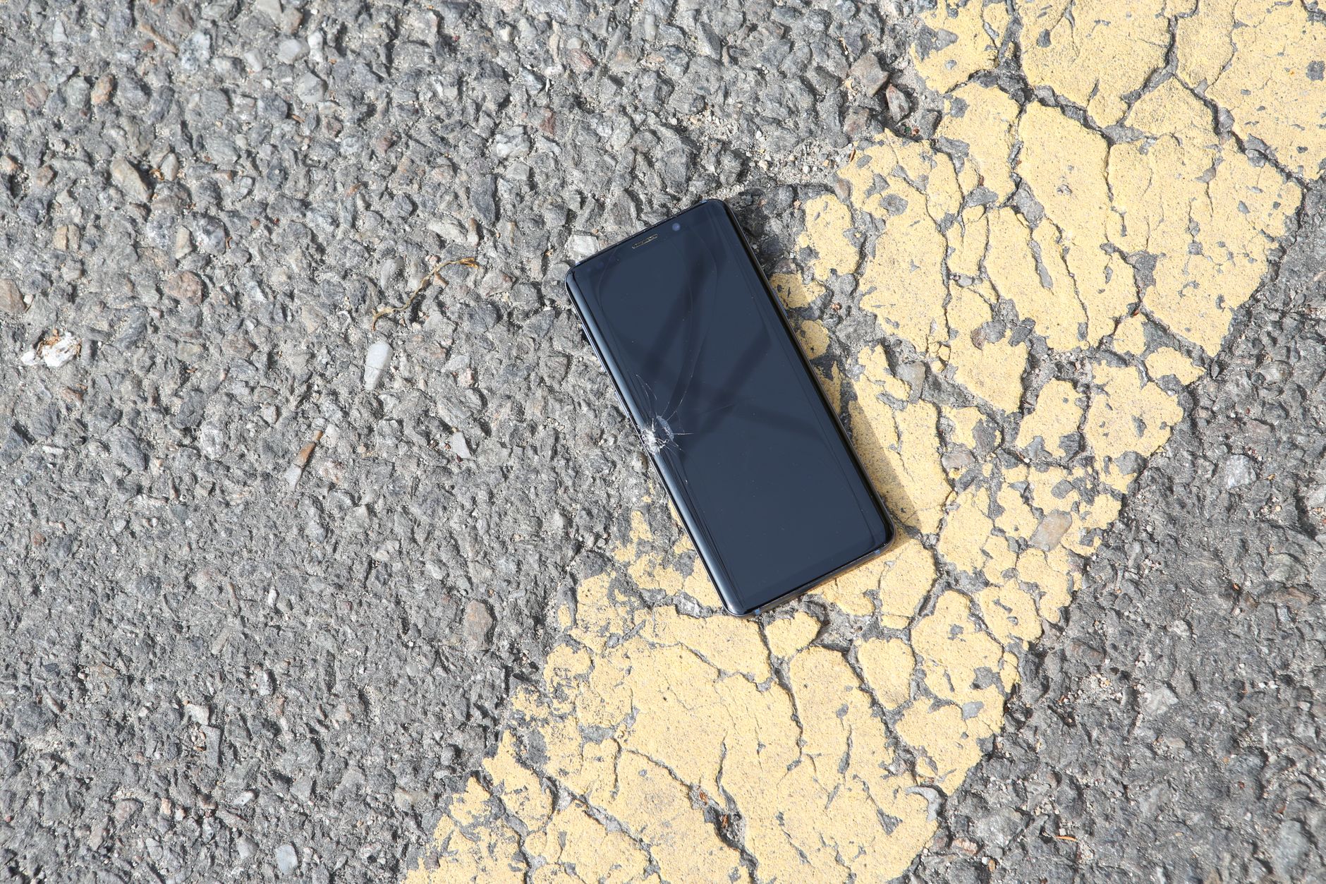damaged cellphone lying down on sunlit asphalt